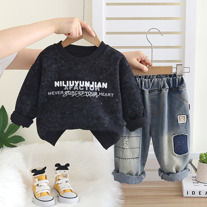 Children's black sweater with text, blue jeans, and yellow sneakers on a white surface.
